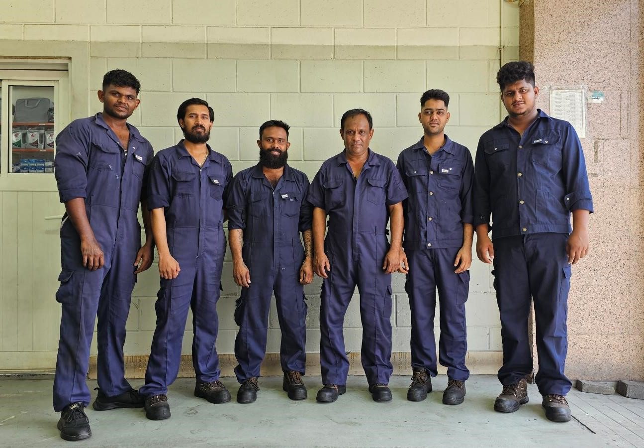 workers in navy blue uniforms standing together indoors at a workshop facility