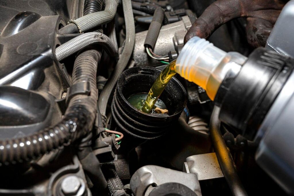 Pouring fresh engine oil into a car engine during maintenance service to ensure smooth performance.